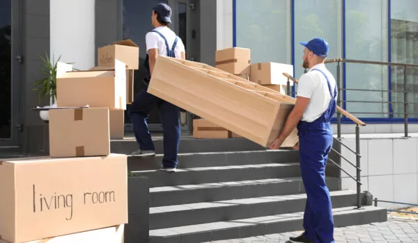Male movers carrying shelving unit into new house